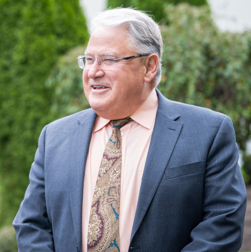 Michael Brogan outside in a blue suit smiling standing in front of Rosary Hall