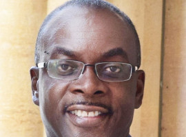 Byron Brown smiling, wearing a suit and yellow tie